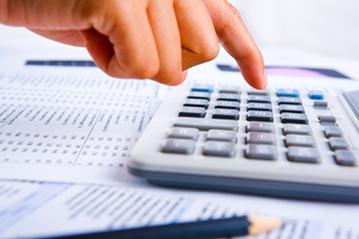 Hand pressing calculator on financial documents.